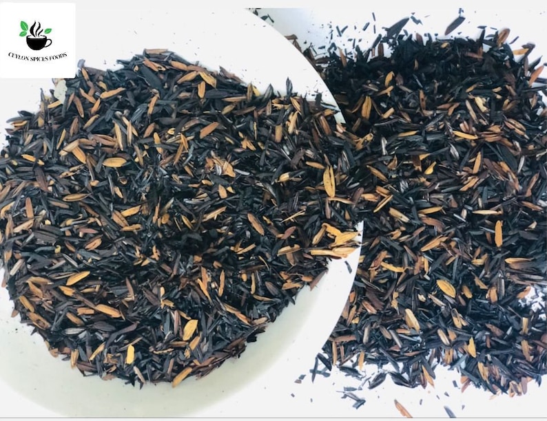May include: A close-up of a bowl filled with loose black and brown tea leaves. The tea leaves are scattered on a white surface.