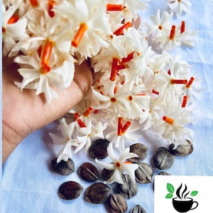 May include: A close-up of white flowers with orange centres, scattered on a light blue surface. There are also several dark brown seeds on the surface. The text "CEYLON SPICES FOODS" is visible in the lower right corner of the image.