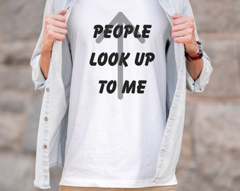 May include: A white t-shirt with a black arrow pointing upwards and the text "PEOPLE LOOK UP TO ME". The shirt is being held open by a person wearing a light blue button-down shirt and khaki pants.