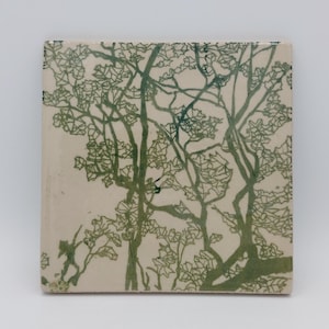 Puede incluir: Un azulejo de cerámica con un diseño de árboles estilizados en verde y blanco. Los árboles están delineados en verde sobre un fondo blanco.