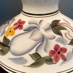 May include: White lampshade with a ruffled top and a floral design. The flowers are painted in shades of red, yellow, blue, and green.