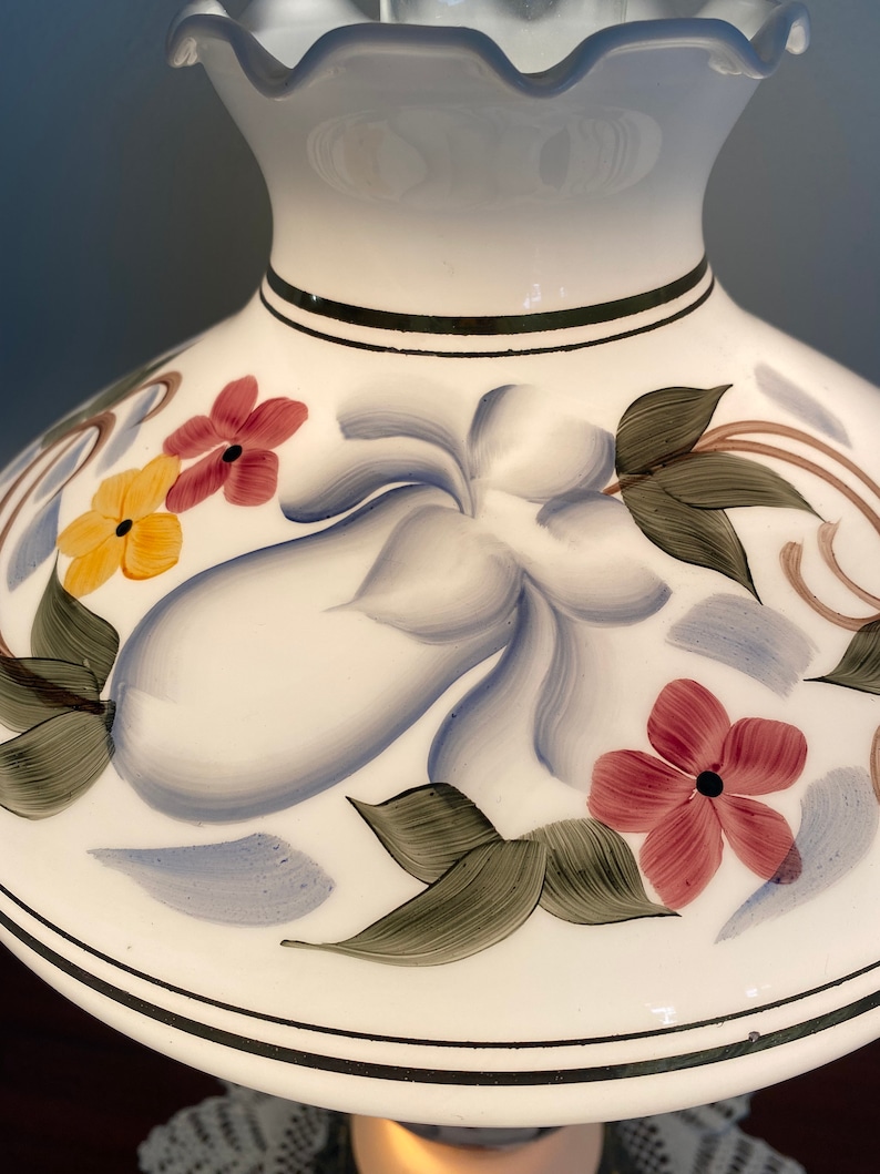May include: White lampshade with a ruffled top and a floral design. The flowers are painted in shades of red, yellow, blue, and green.