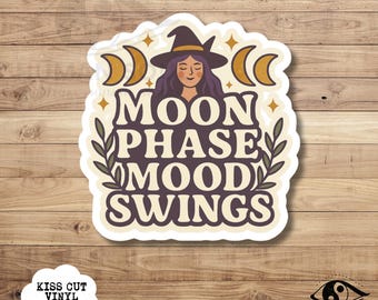 May include: A white kiss-cut vinyl sticker with the text "MOON PHASE MOOD SWINGS" in a retro font. The design includes a witch with a hat, crescent moons, and stars. The sticker also has the text "KISS CUT VINYL STICKER".