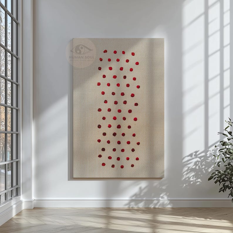May include: A large, rectangular canvas art piece with a beige background. A vertical pattern of red dots is arranged in the center. The artwork is hanging on a white wall, with a window and plant visible in the background.