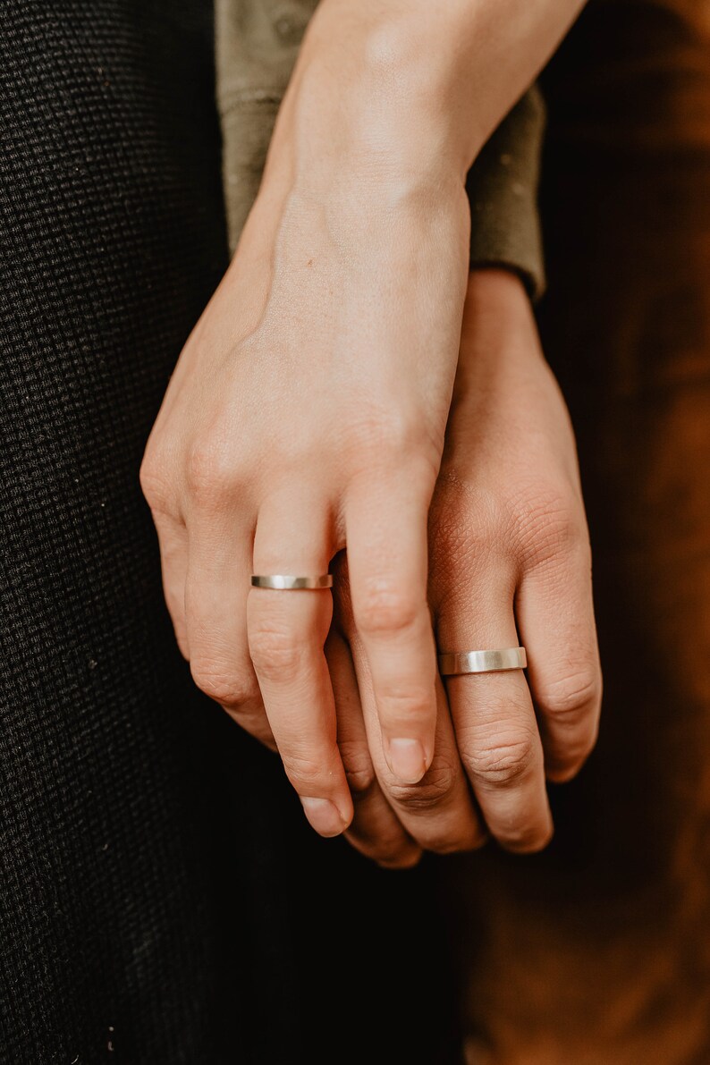 Handmade Silver Wedding Band Set. This photo shows two forged sterling silver rings. (Rings are shown on man's and woman's fingers)