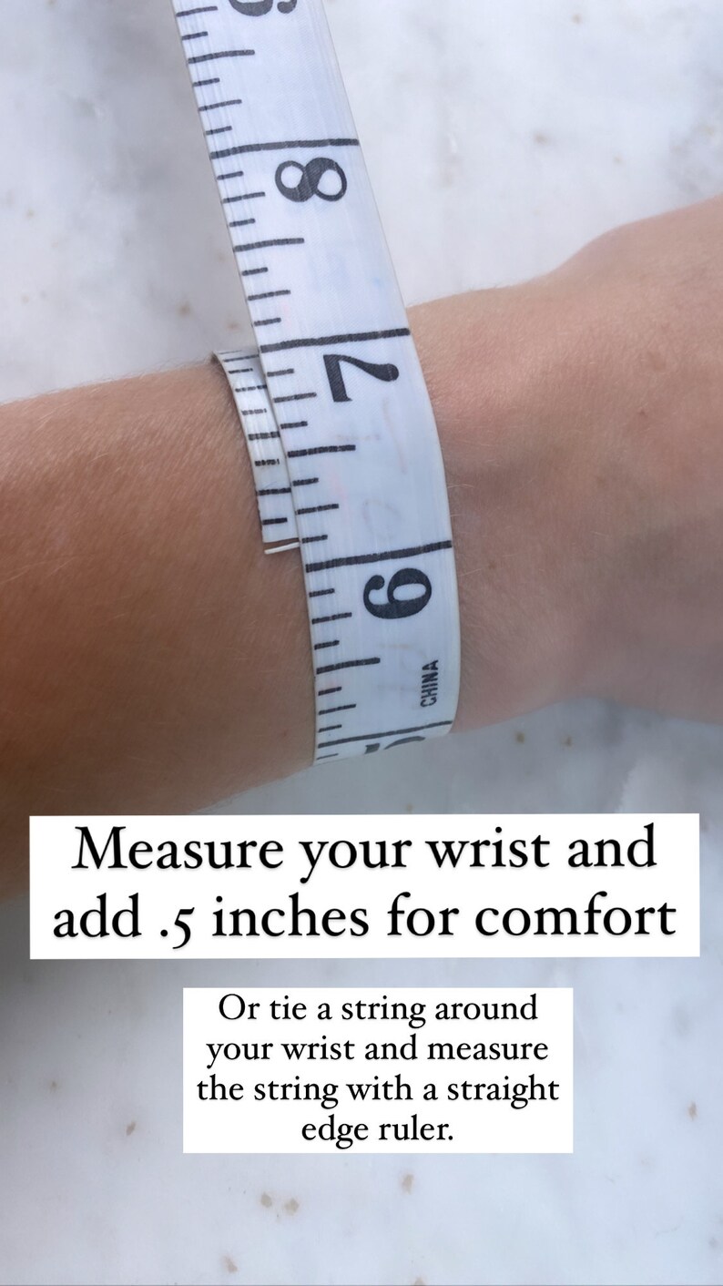 May include: A white measuring tape wrapped around a wrist to show how to measure for a bracelet. The text reads "Measure your wrist and add .5 inches for comfort. Or tie a string around your wrist and measure the string with a straight edge ruler."