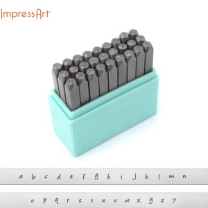 May include: A set of 26 metal letter stamps in a turquoise plastic case. The stamps are arranged in alphabetical order and include a question mark. The letters are in a cursive font.