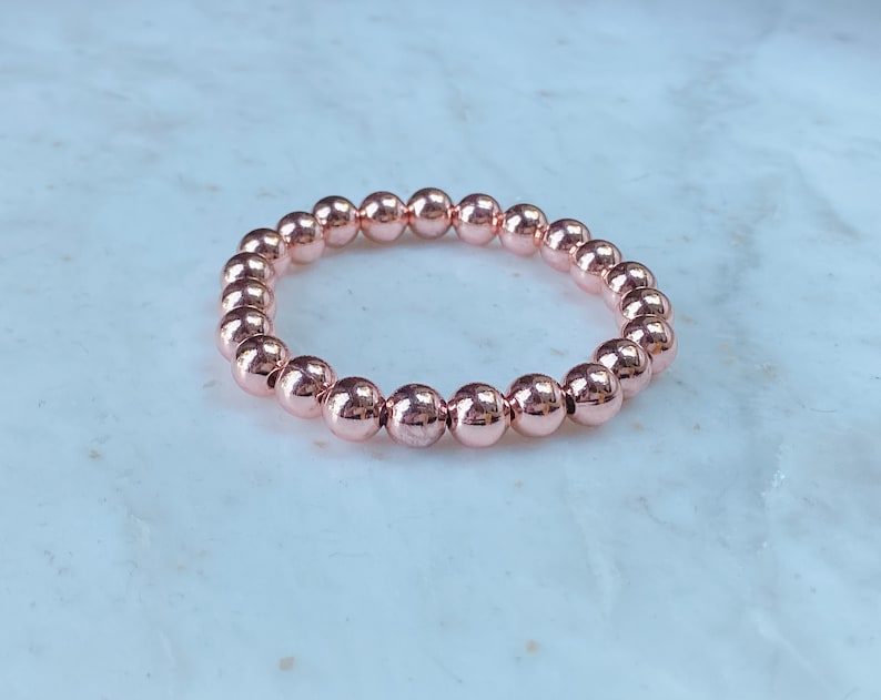 May include: A rose gold beaded bracelet with round beads.