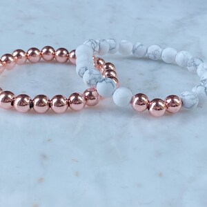 May include: Two bracelets, one with rose gold beads and one with white marble beads.