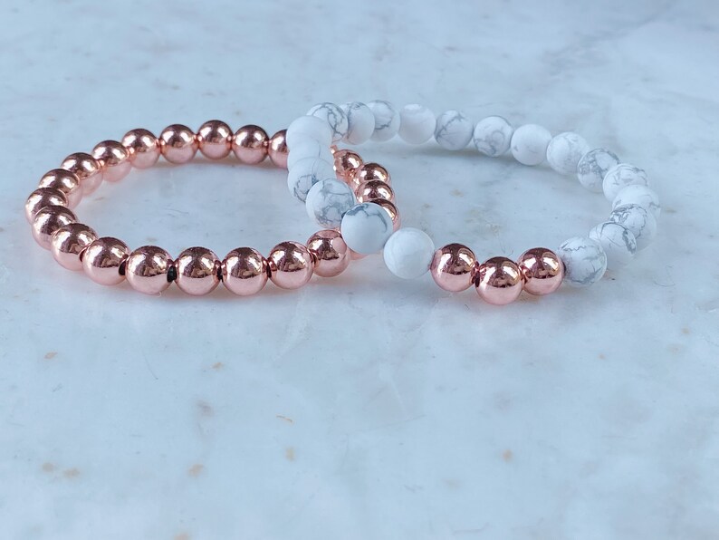 May include: Two bracelets, one with rose gold beads and one with white marble beads.
