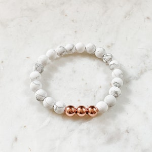 May include: White and gray marble bead bracelet with three rose gold beads.