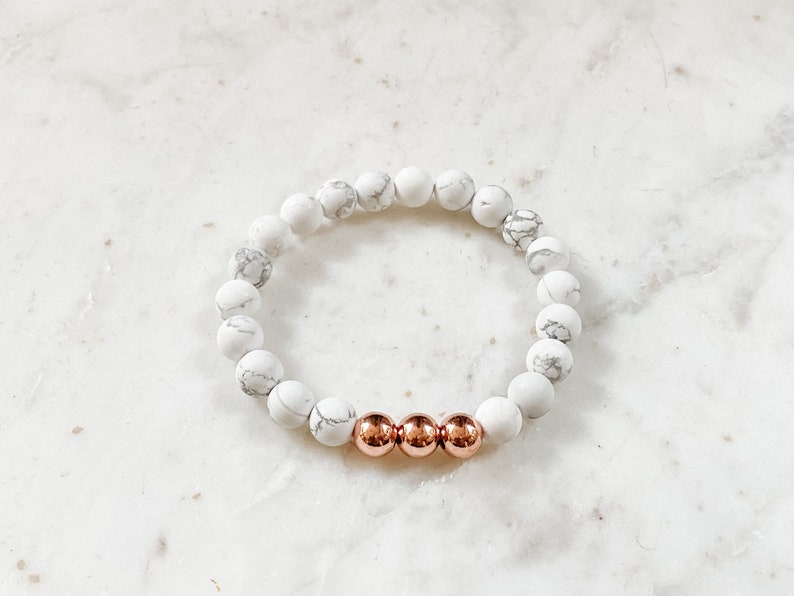 May include: White and gray marble bead bracelet with three rose gold beads.
