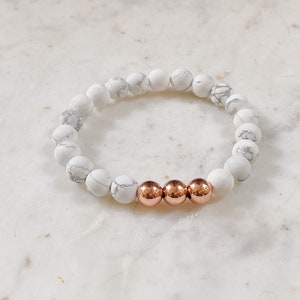 May include: White and gray marble bead bracelet with three rose gold beads.