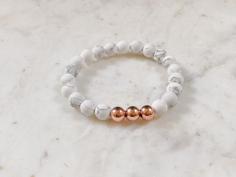 May include: White and gray marble bead bracelet with three rose gold beads.