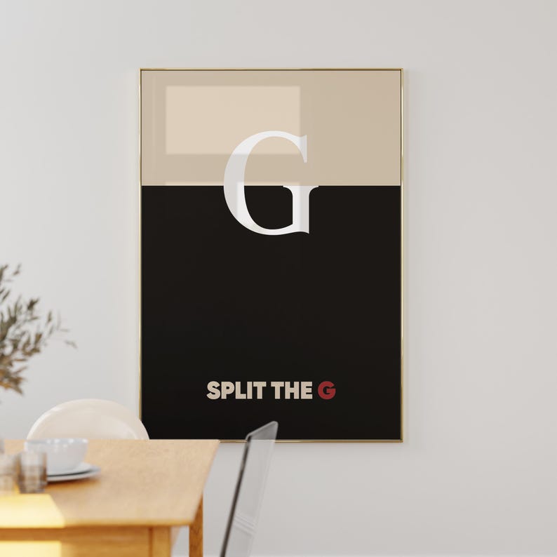 Pode incluir: Uma impress&atilde;o art&iacute;stica emoldurada com uma borda dourada. A obra apresenta uma grande letra "G" branca sobre um fundo de duas cores bege e preto. O texto "SPLIT THE G" est&aacute; na parte inferior, com o "G" em vermelho.
