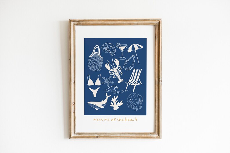 May include: A framed print with a blue background and white illustrations of beach-themed items, including a swimsuit, a beach chair, a seashell, a lobster, a starfish, a cocktail glass, an umbrella, a net bag, and a whale. The text "meet me at the beach" is at the bottom of the print.