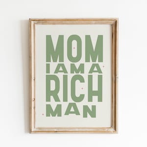 May include: A framed print with the text "MOM I AM A RICH MAN" in green letters on a beige background.