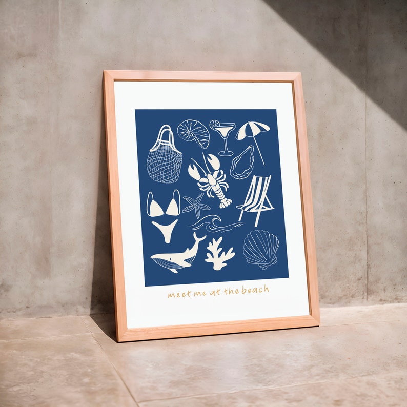 May include: A framed print with a blue background and white illustrations of beach-themed items, including a seashell, a lobster, a swimsuit, a beach chair, a wave, a starfish, a net bag, a cocktail glass, an umbrella, and a whale. The text "meet me at the beach" is at the bottom of the print.