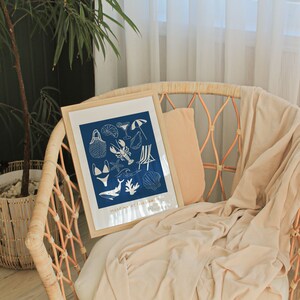 May include: A framed print with a blue background and white illustrations of various summer-themed items, including a beach umbrella, a seashell, a lobster, a starfish, and a whale. The text "meet me at the beach" is printed at the bottom of the print.