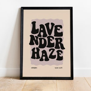 May include: A black framed print with a light pink background and the text "Lavender Haze" in black, stylized lettering. The text is from the song "Lavender Haze" by Taylor Swift.