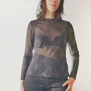 May include: A black sheer long-sleeved top with silver glitter. The top has a round neckline and is semi-transparent.