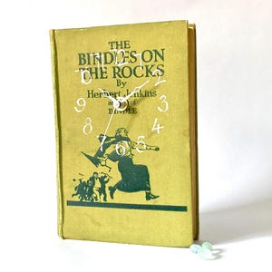 May include: A white ceramic mug with a black handle and the text "But First, Coffee" in a handwritten style. The mug is on a white surface. The mug is approximately 4 inches tall.