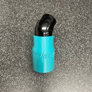 以下が含まれることがあります： 側面に「マキタ」と印刷されたターコイズブルーの3Dプリントアダプター。アダプターは掃除機ホースに接続するように設計されています。