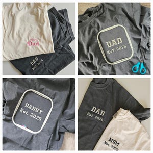 May include: Four t-shirts with embroidered text. Two gray t-shirts with "DAD EST 2025", one gray t-shirt with "DADDY Est. 2025", and one white t-shirt with "Girl Dad" in pink thread and "DAD EST. 2024" in black thread.
