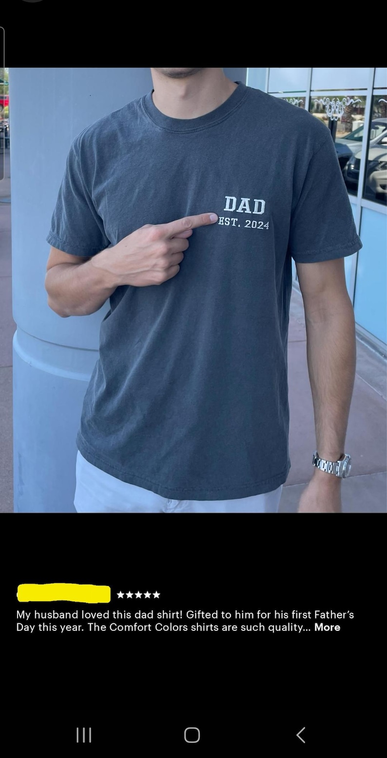 May include: A dark gray t-shirt with the text "DAD EST. 2024" printed on the front.