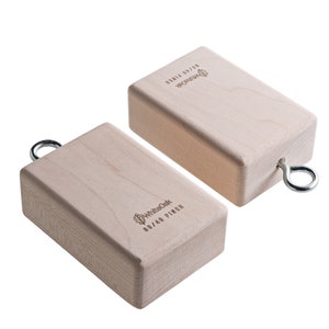 May include: Two wooden climbing holds with a metal ring for hanging. The holds are made of maple wood and have a natural finish. The holds are labeled "80/40 Pinch" and "Double Dyno".