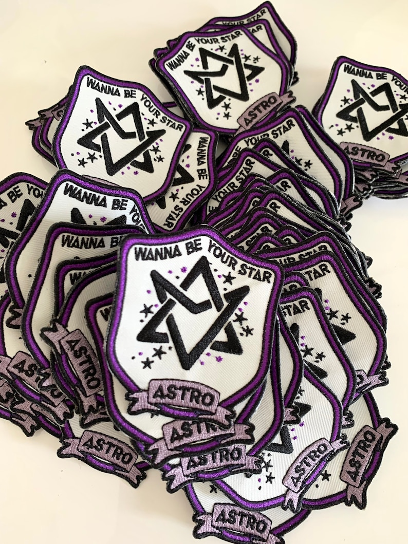 May include: A stack of white fabric patches with a purple border. The patches feature a black and white star design with the text "WANNA BE YOUR STAR" and "ASTRO" in a banner.