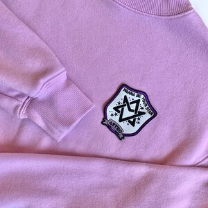 May include: A lavender sweatshirt with a black and white patch featuring a star design and the text "Wanna be your star" and "ASTRO".