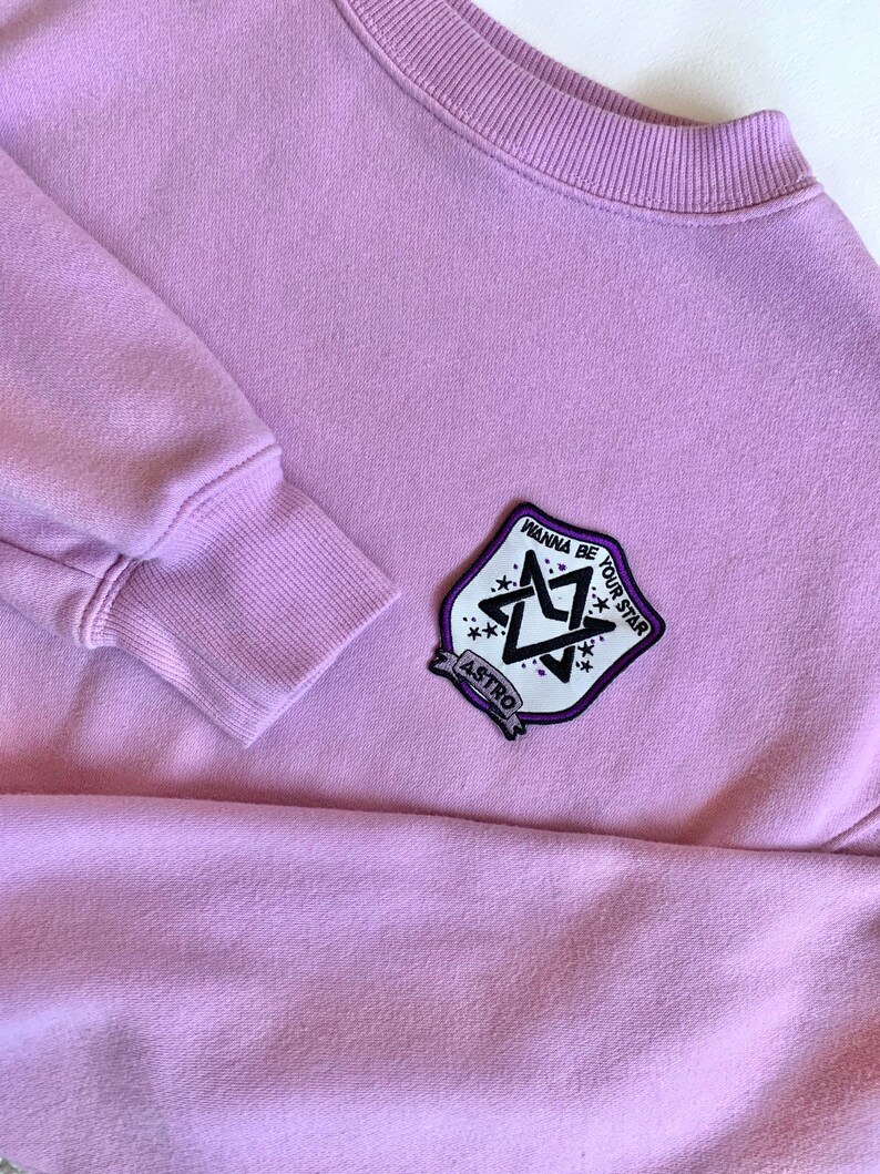 May include: A lavender sweatshirt with a black and white patch featuring a star design and the text "Wanna be your star" and "ASTRO".