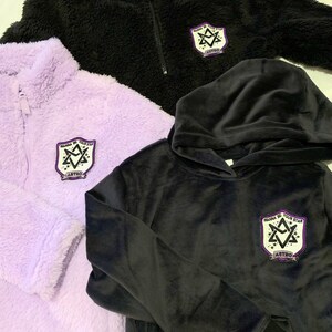 May include: Three different styles of sweatshirts with a purple and white patch that says "Wanna Be Your Star" and "ASTRO" in black lettering. The sweatshirts are black, purple, and black with a hood.