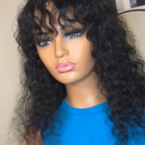 May include: A black curly wig with bangs on a mannequin head. The mannequin is wearing a blue t-shirt with the text "Librarian est. 84" printed on it.