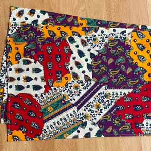 Peut inclure: Deux sets de table colorés avec un motif paisley dans des tons de rouge, jaune, vert, violet et blanc.