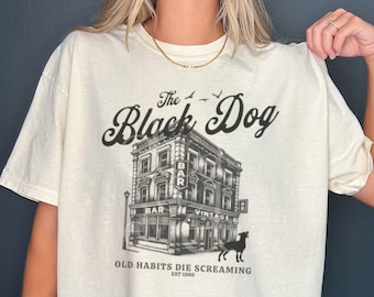 May include: A white t-shirt with a black and white graphic of a building with the text "The Black Dog" and "Old Habits Die Screaming Est 1980".