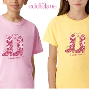 Puede incluir: Una camiseta rosa claro y una camiseta amarilla, cada una con un gr&aacute;fico rosa oscuro de dos botas vaqueras decoradas con patrones de flores y estrellas. El texto "i knew it, i knew you" est&aacute; impreso en rosa oscuro alrededor de las botas.
