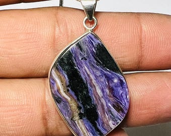 May include: A silver chain necklace with a pendant featuring a large, irregularly shaped, purple and black stone. The stone has a swirling, marbled pattern.
