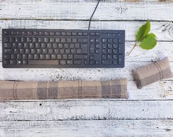 以下が含まれることがあります： 白い木製の表面に、黒いキーボードと、茶色とベージュの格子模様の腰痛用クッションと、茶色とベージュの格子模様の小さなクッションが置かれています。