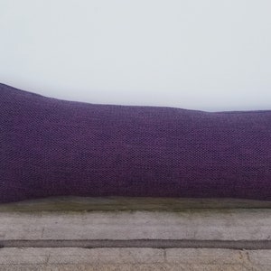 Può includere: Un cuscino fermaporta lungo e viola realizzato in tessuto strutturato.