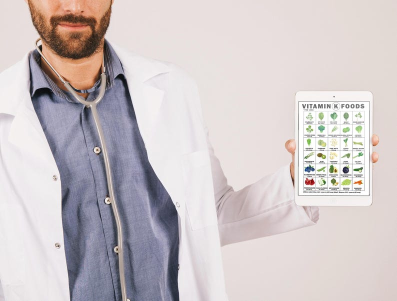 May include: A person wearing a white lab coat and a stethoscope around their neck holds a tablet displaying a chart of Vitamin K foods. The chart features various vegetables, fruits, and other food items, with the text "VITAMIN K FOODS" at the top.