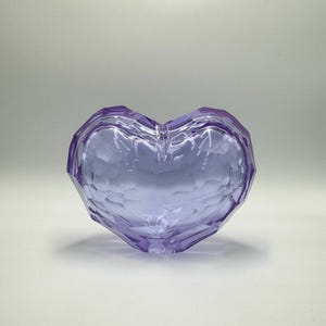 Könnte beinhalten: Eine herzförmige Schale aus violettem Glas mit strukturierter Oberfläche.