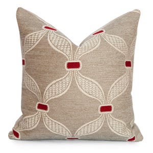 May include: A decorative throw pillow with a beige background and a repeating pattern of white, leaf-like shapes connected by red rectangles. The pillow has a textured appearance and is designed for home decor.