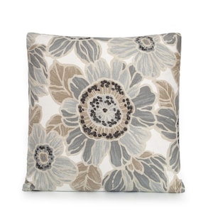 May include: A decorative throw pillow with a floral pattern in shades of gray, brown, and white. The pillow features a large, stylized flower in the center with smaller flowers and leaves surrounding it.