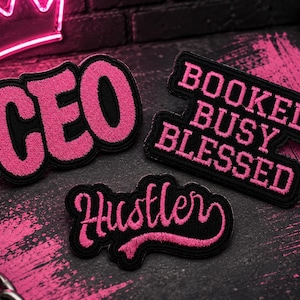 May include: Three embroidered patches with black backgrounds and pink lettering. One patch reads CEO in bold letters, another reads BOOKED BUSY BLESSED in a stacked block font, and the third patch features the word Hustler in a cursive script font.