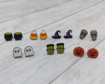 May include: A set of 10 Halloween themed earrings. The earrings are made of wood and feature various designs, including ghosts, pumpkins, candy corn, witches hats, cauldrons, and sugar skulls.