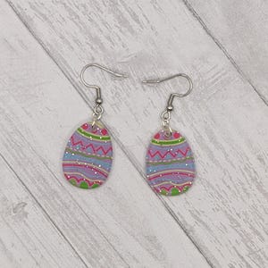 May include: A pair of silver dangle earrings with a purple, pink, green, and white patterned egg design.