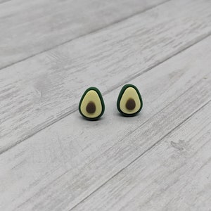 May include: A pair of avocado-shaped earrings with green and yellow paint. The earrings are small and have a simple design.