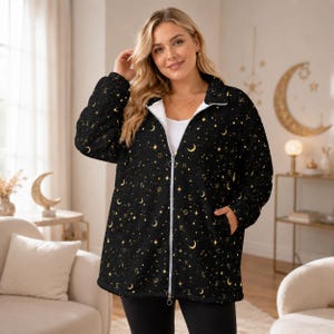 May include: Black zip-up jacket with a celestial pattern of gold moons, stars, and zodiac symbols. The jacket has a white interior lining and a white zipper. The jacket has two pockets and a collar.